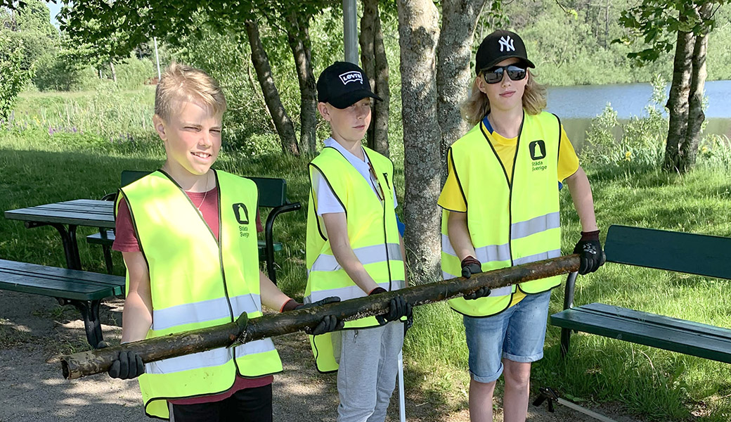 Tre unga innebandylirare med ett järnrör som de hittat i naturen.