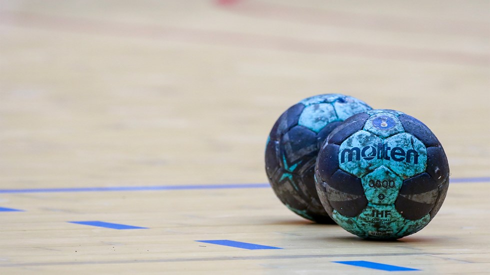 två blå bollar ligger på golvet på en handbollsplan
