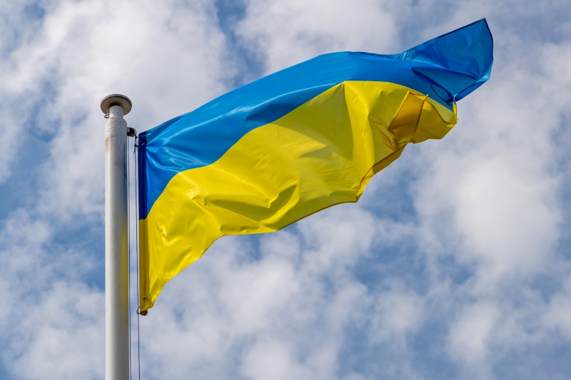 Ukrainas flagga mot blå himmel med lätta moln.