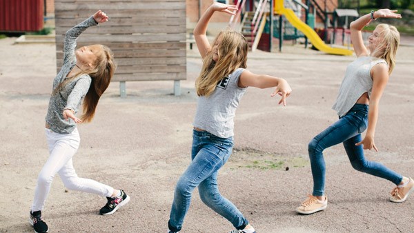 Tre flickor som dansar på en skolgård