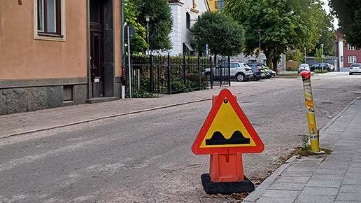 Ett vägmärke för b yggnation pågår står på en grusbelagd stadsgata.