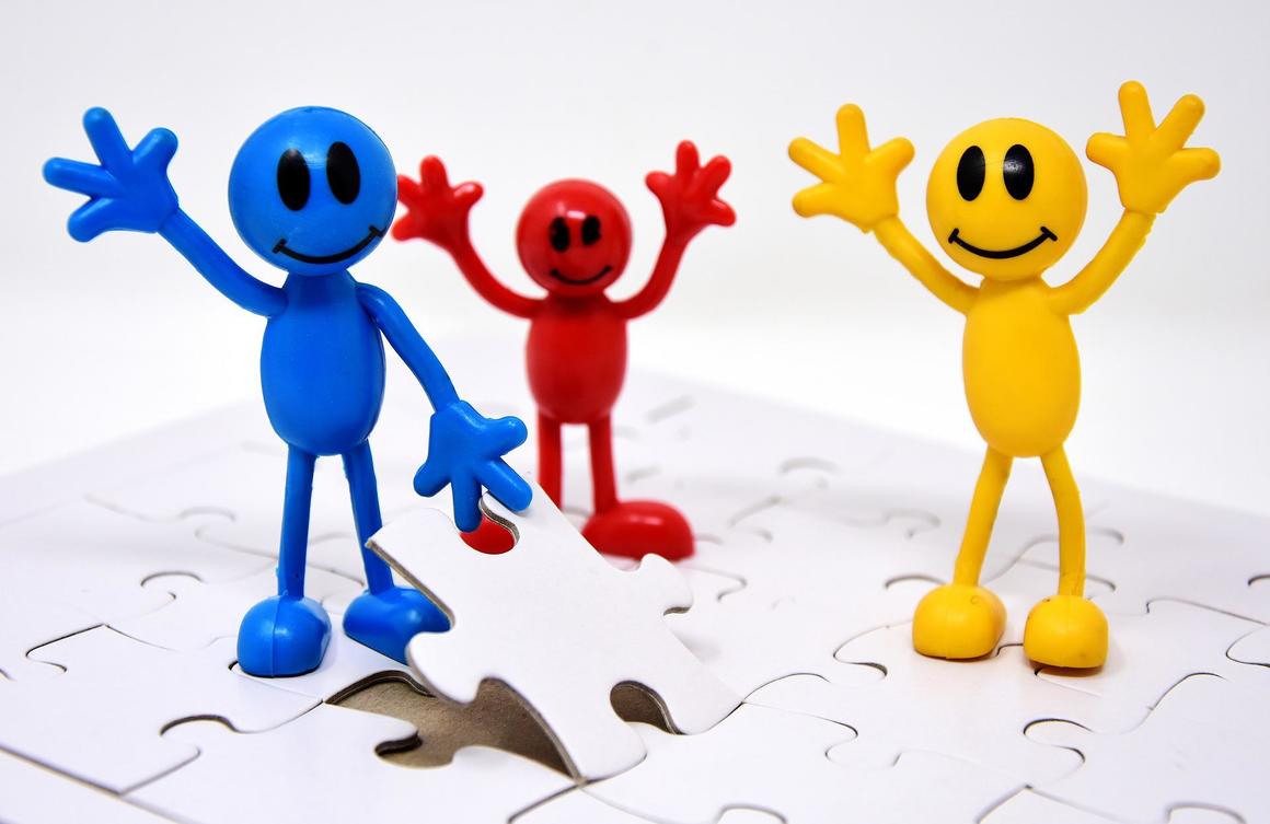 Tre glada figurer i blått, rött och gult står på ett pussel